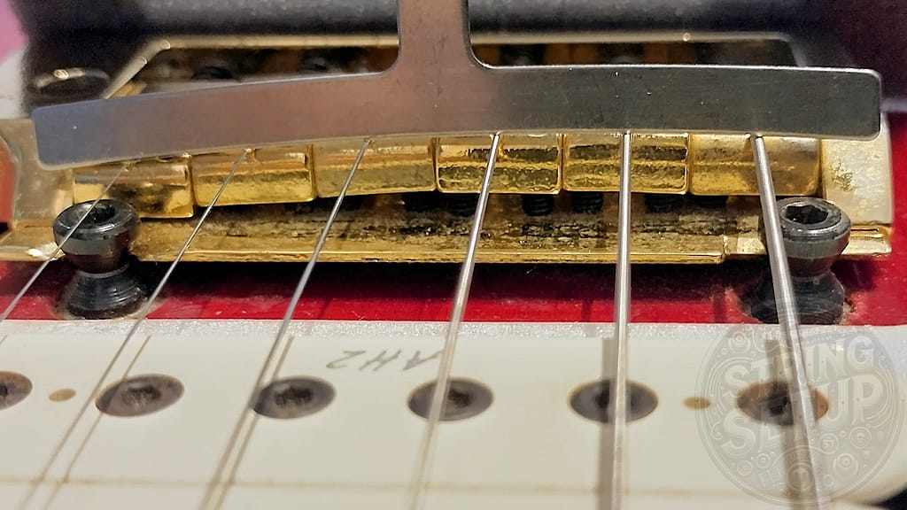 Radius gauge appoggiato sopra le corde per valutare il feel dell’action e la coerenza dell’altezza delle sellette rispetto al radius della tastiera.
