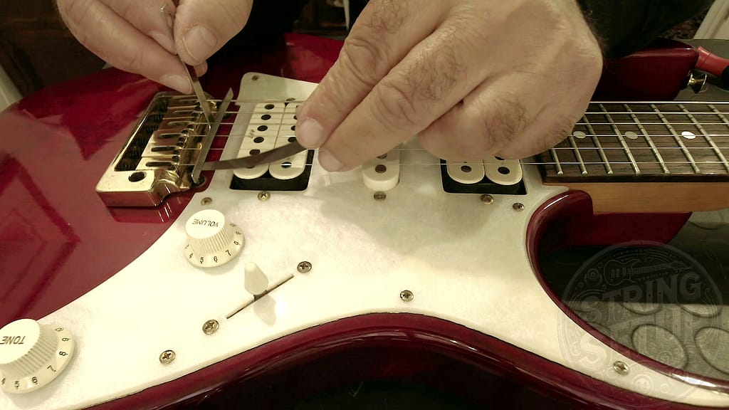 Misurazione dell’action della chitarra con spessimetro inserito tra corda e radius gauge per ottenere un setup preciso, misurabile e ripetibile.